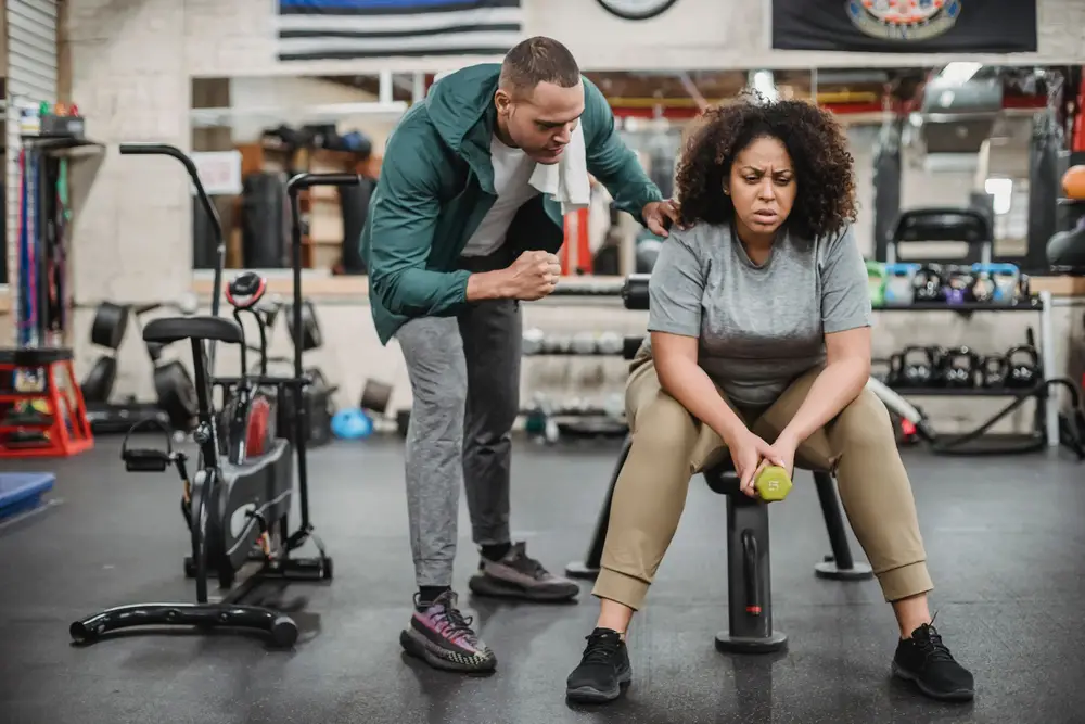 A trainer guiding a client through a seated exercise in a gym