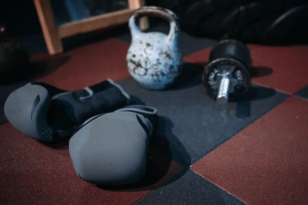 Kettlebell, dumbbell and boxing gloves on a gym floor